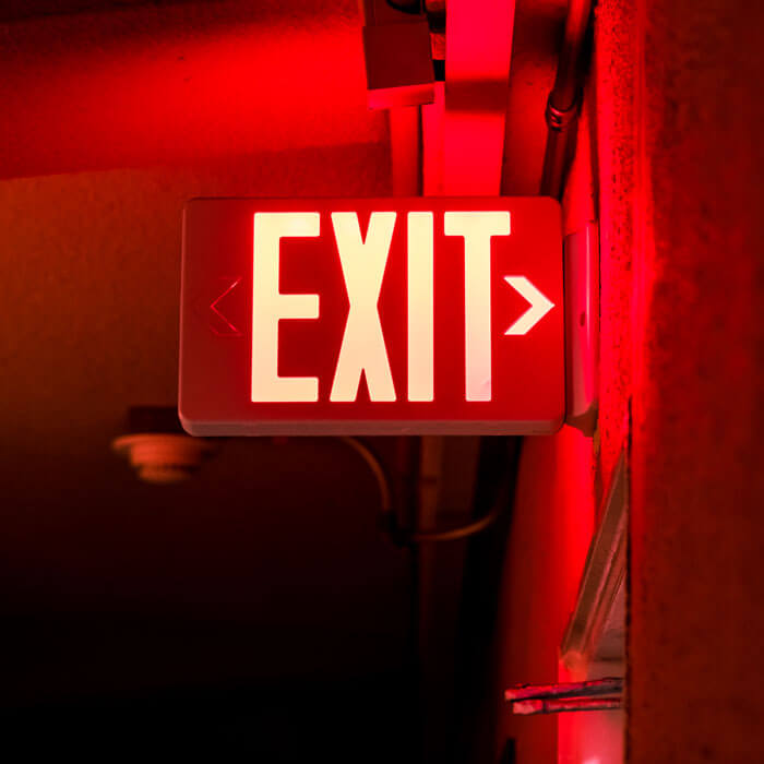 Bright red illuminated exit sign mounted on the wall for emergency lighting, in Phoenix, AZ