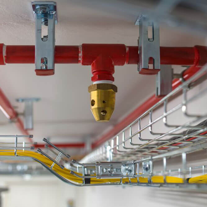 Red fire suppression system pipes with a brass nozzle installed on the ceiling in Phoenix, AZ